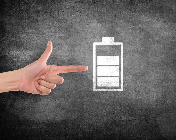 Hand pointing battery charging icon on blackboard